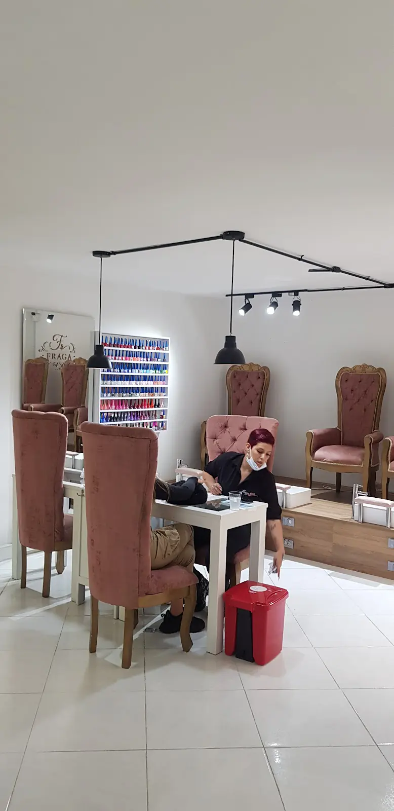 Salón de Fraga con sillas rosadas, lámparas colgantes y estaciones de manicura